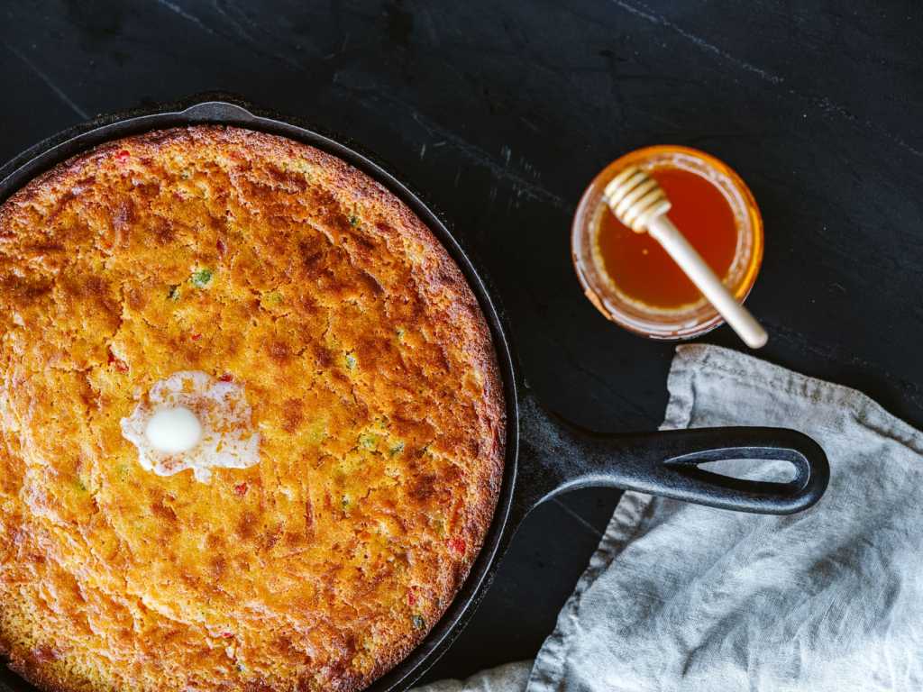 A rustic cast iron skillet filled with golden cornbread, showcasing its crispy crust and fluffy texture.