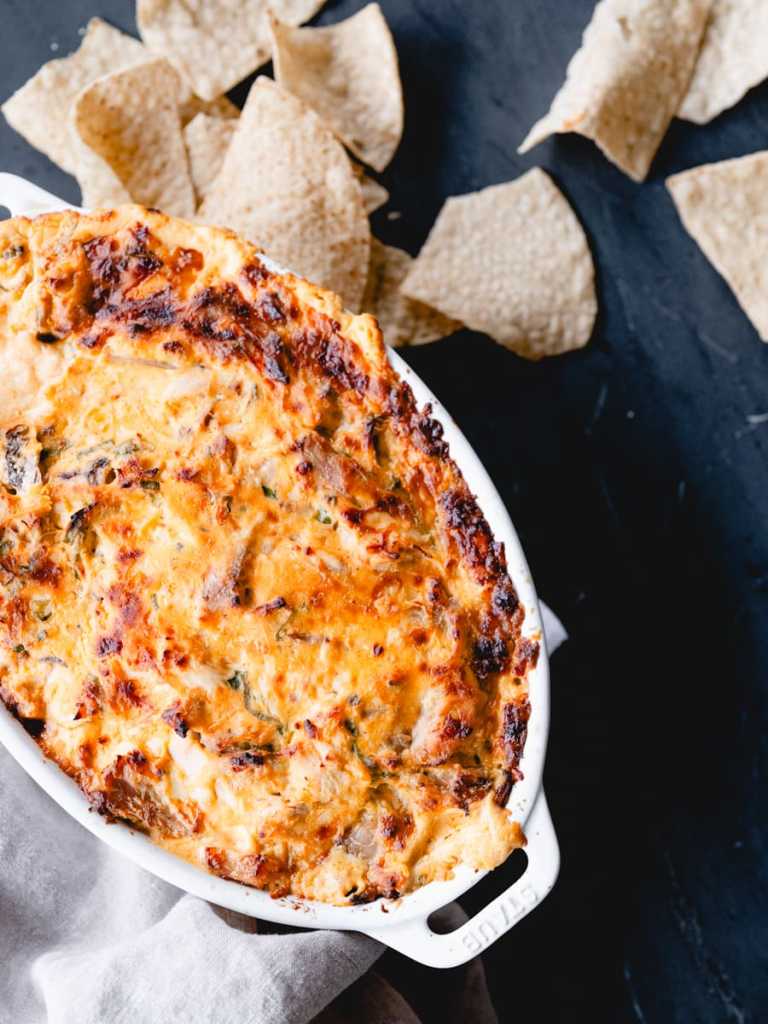 A bubbly dish of buffalo chicken dip with tortilla chips.